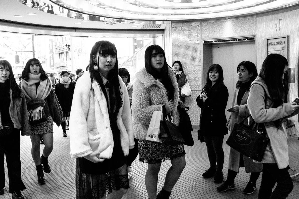 Group of young women in winter coats standing in an underground shopping concourse