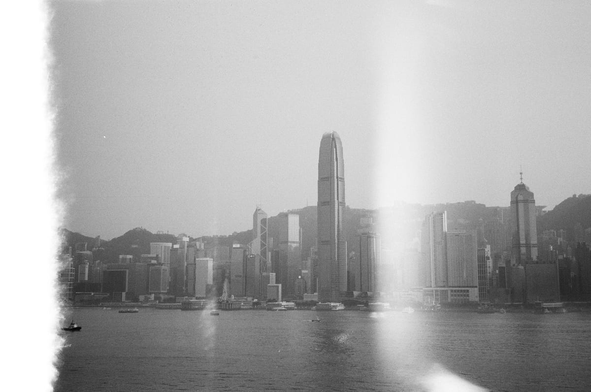 Hazy sun-washed view of the Hong Kong Island skyline across the harbour with IFC tower prominent at center